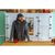 Bearded man in his 40s standing in a bright kitchen, with a red coffee mug. Man is wearing a dark Stormy Kromer cap, a blue, gray and brown plaid flannel shirt and a gray waxed cotton vest.