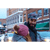 Photo of a man and woman walking down the street of a busy, small town downtown. The man is wearing the North Star Plaid Mackinaw Cap and a dark gray wool coat, the woman is wearing a pink pompom knit hat and a black and white plaid jacket.