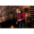 Image of a young man tending to a fire in a large stone fireplace. He is wearing a charcoal Watch Cap, red shirt and navy plaid vest.