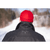 Back view photo of a man standing on a long snowy hiking trail, wearing a charcoal Mackinaw Coat and red Stormy Kromer Cap. Both items show the embroidered Stormy Kromer signature on the back.