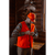 Photo of a man inside a log home buttoning up his blaze orange Button Vest. He is also wearing a blaze orange Stormy Kromer cap.