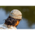 Back view of a man with long dark hair looking out over the water and wearing a light tan Trail Cap and plaid shirt.