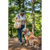 Image of a woman standing with her dog in front of a green wooded area. The woman is wearing a green Forager Hat and is carrying a large tote bag. Her golden retriever is wearing a colorful bandana.