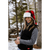 Photo of woman in her 20s with long hair standing in a snowy forest, laughing, wearing a black Stomy Kromer vest and a red/black plaid Stormy Kromer Aviator Hat.