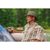 Photo of a man in a light colored plaid shirt on a pontoon boat, holding a canned beverage, smiling and wearing The Mesh Hiker hat in Fern.