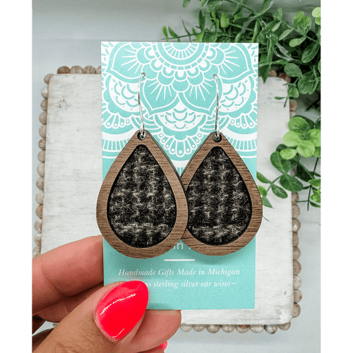 Pair of tear-drop shaped earrings made of a dark wood framing black and brown wool fabric
