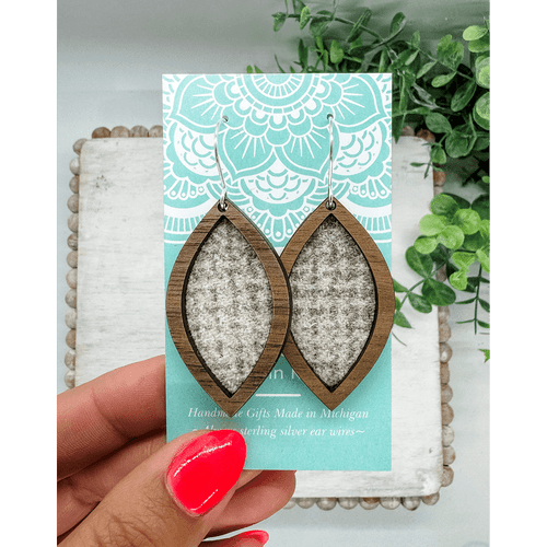 Pair of leaf shaped earrings made of a dark wood framing gray and white wool fabric